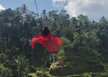 Woman in red dress on Bali swing.