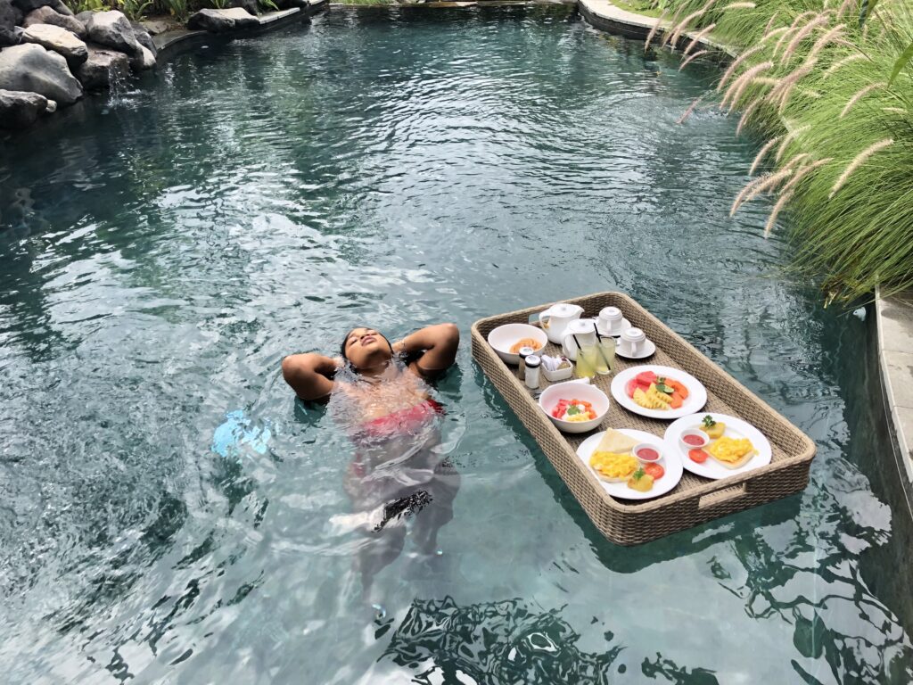 woman bathing in pool next to floating breakfast.