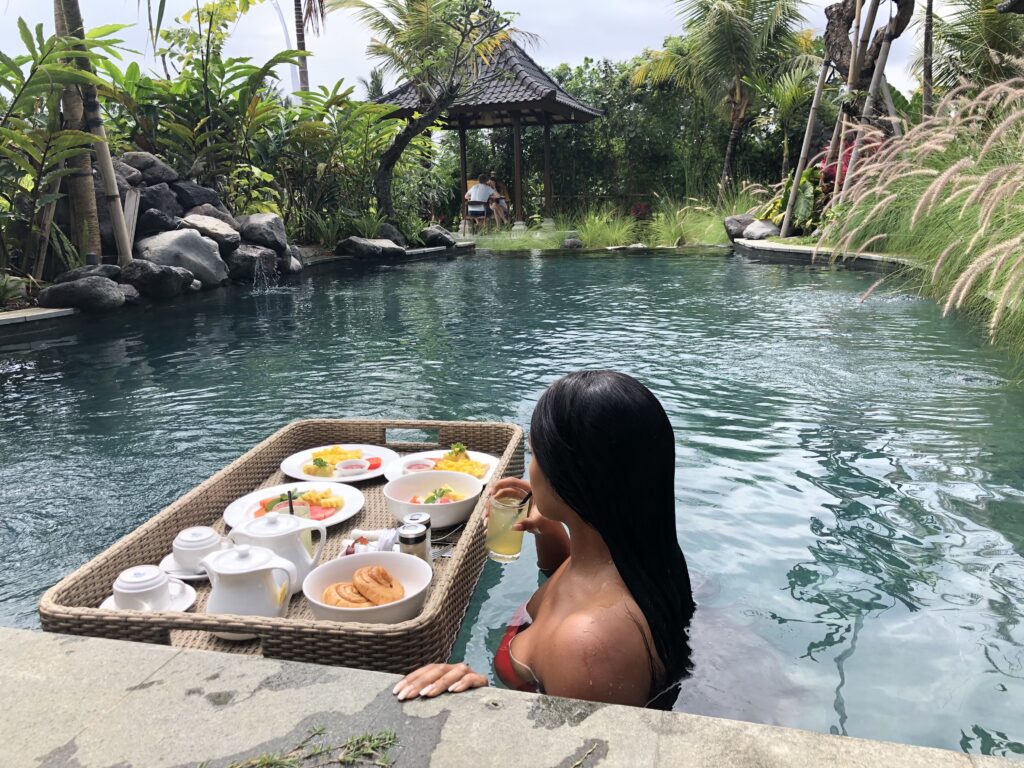 Woman sipping a drink in the pool next to floating breakfast.