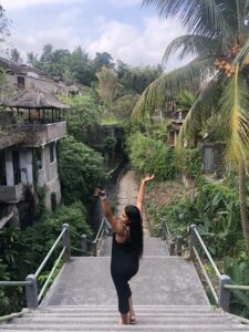 woman with arms up standing on steps in downtown ubud, Bali.
