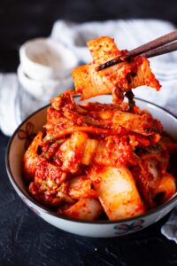 Korean kimchi held by chopsticks.